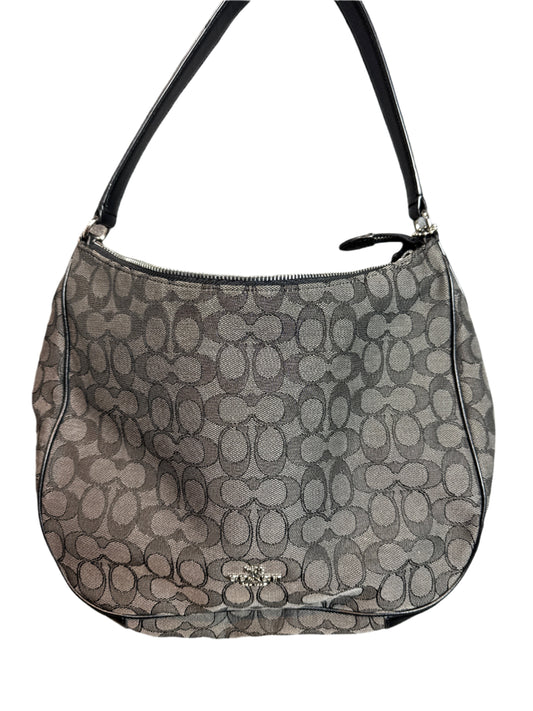 Coach handbag with monogram pattern on a light gray background